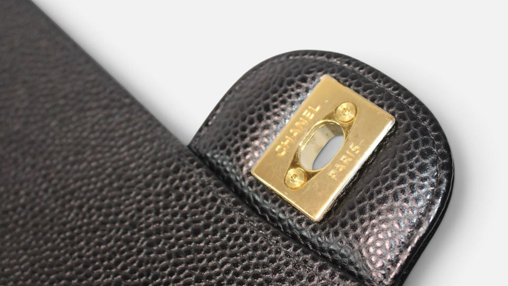 Detalle del cierre dorado con logo de Hibiscx's Archive en bolso CHANEL de piel de caviar negra acolchada