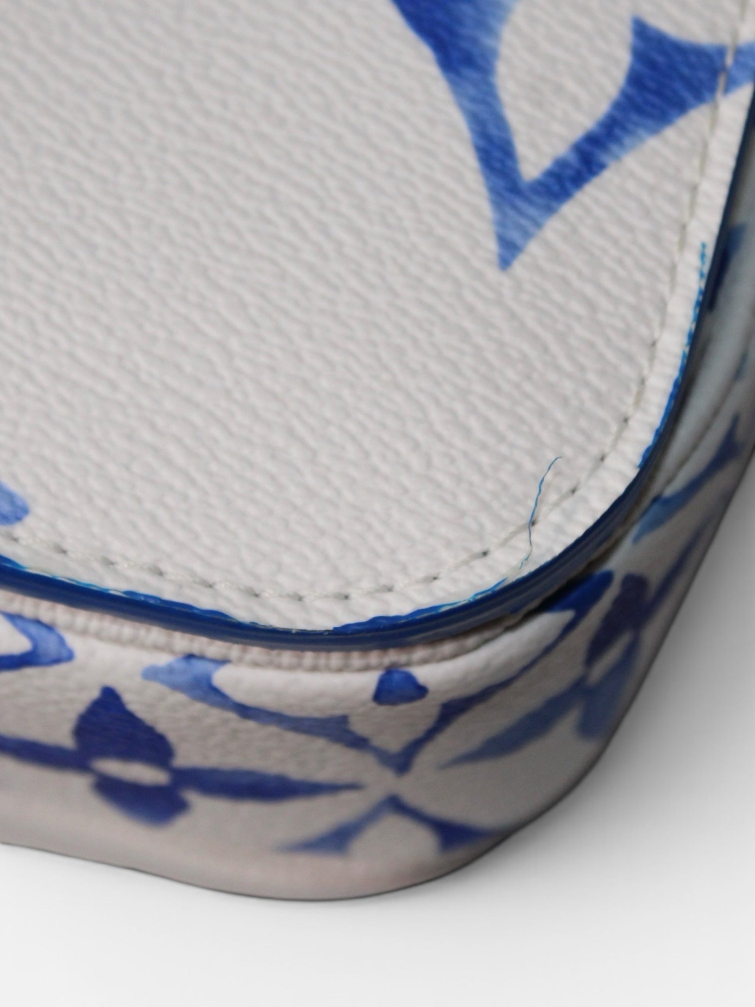 Detalle de piel granulada blanca con estampado de monograma azul de bolso Hibiscx's Archive