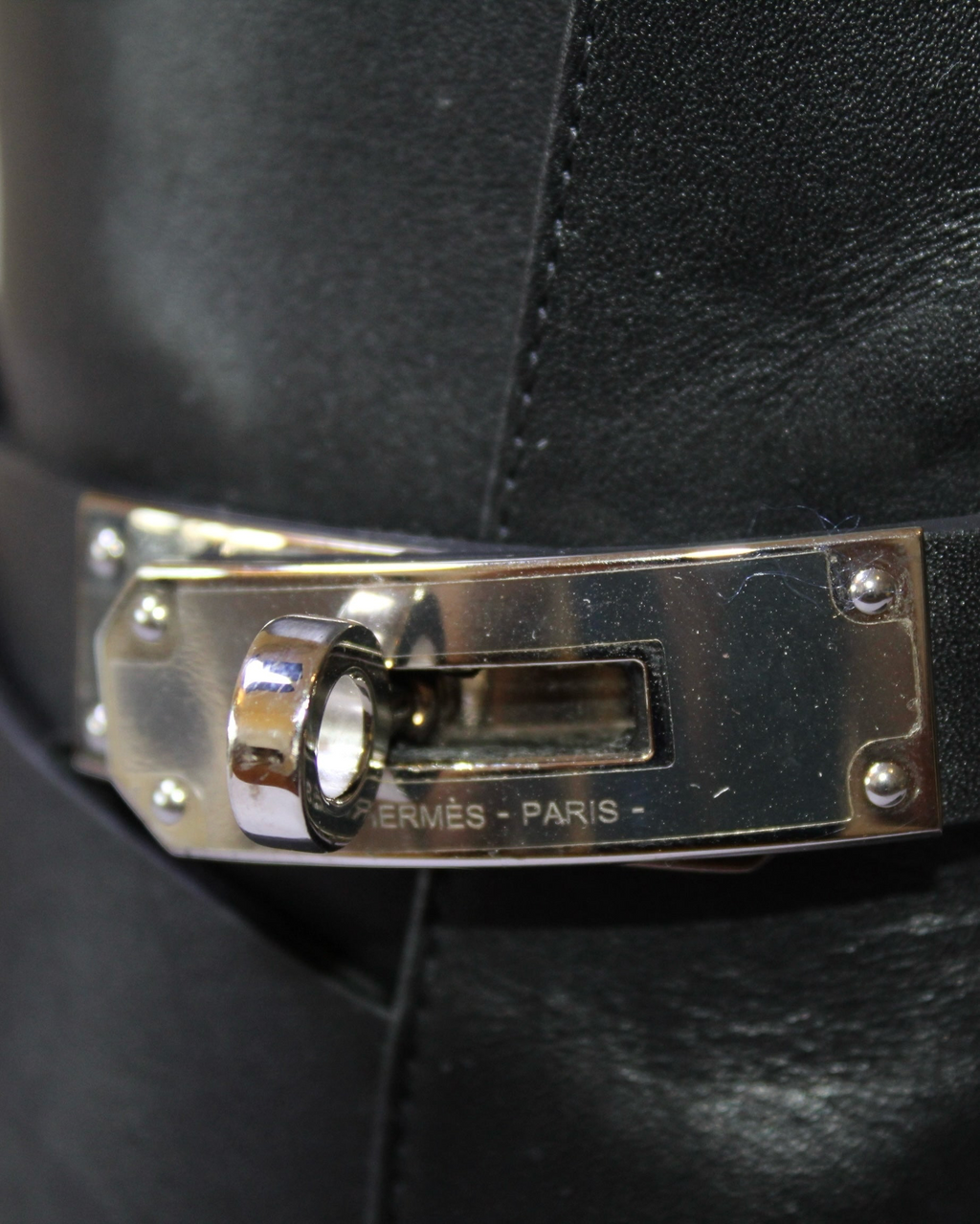 Detalle de hebilla metálica plateada con logo Hermès en botines de piel negra de Hibiscx's Archive