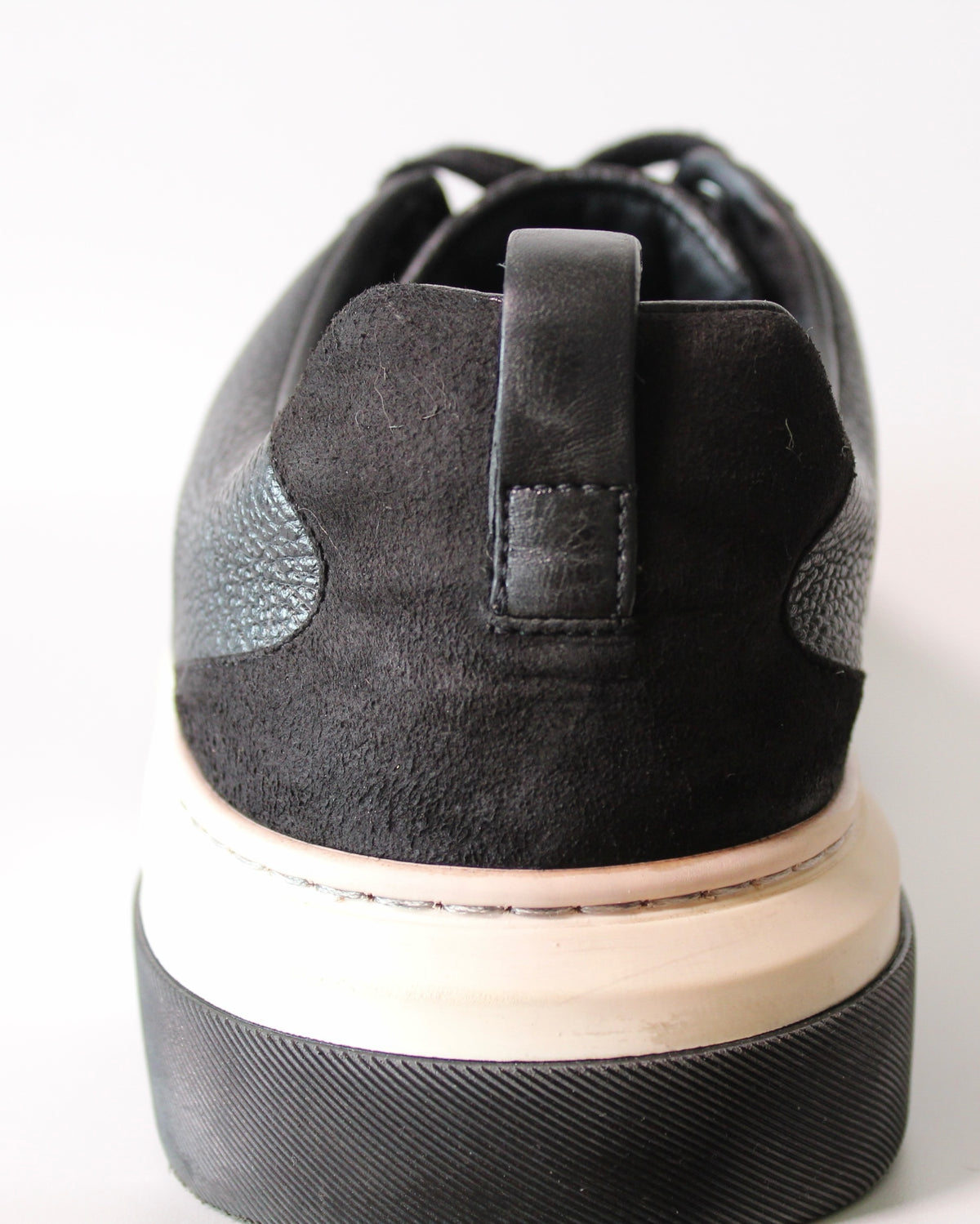 Detalle del talón de tenis Hibiscx's Archive en piel y gamuza negra con suela de plataforma bicolor.